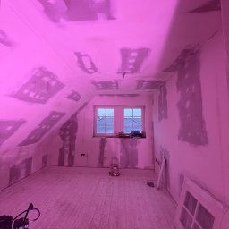 Dawid Kliczkowski - Pokój na poddaszu w Szczecinie w trakcie przygotowania ścian do malowania, widoczne załatane płyty gipsowo-kartonowe, kompresor i okno.