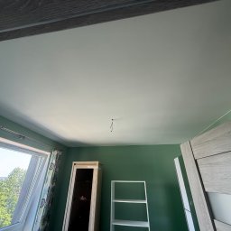 Dawid Kliczkowski - Pomieszczenie po malowaniu ścian na zielono i sufitu na biało. Widoczne okno dachowe, drzwi, regał i szafka. W suficie wystają kable.