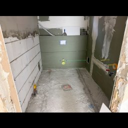 Dawid Kliczkowski - Łazienka w trakcie remontu: ściany z płyt karton-gips, widoczne instalacje, podłoga przygotowana pod wylewkę. Laserowy niwelator wyznacza poziom.