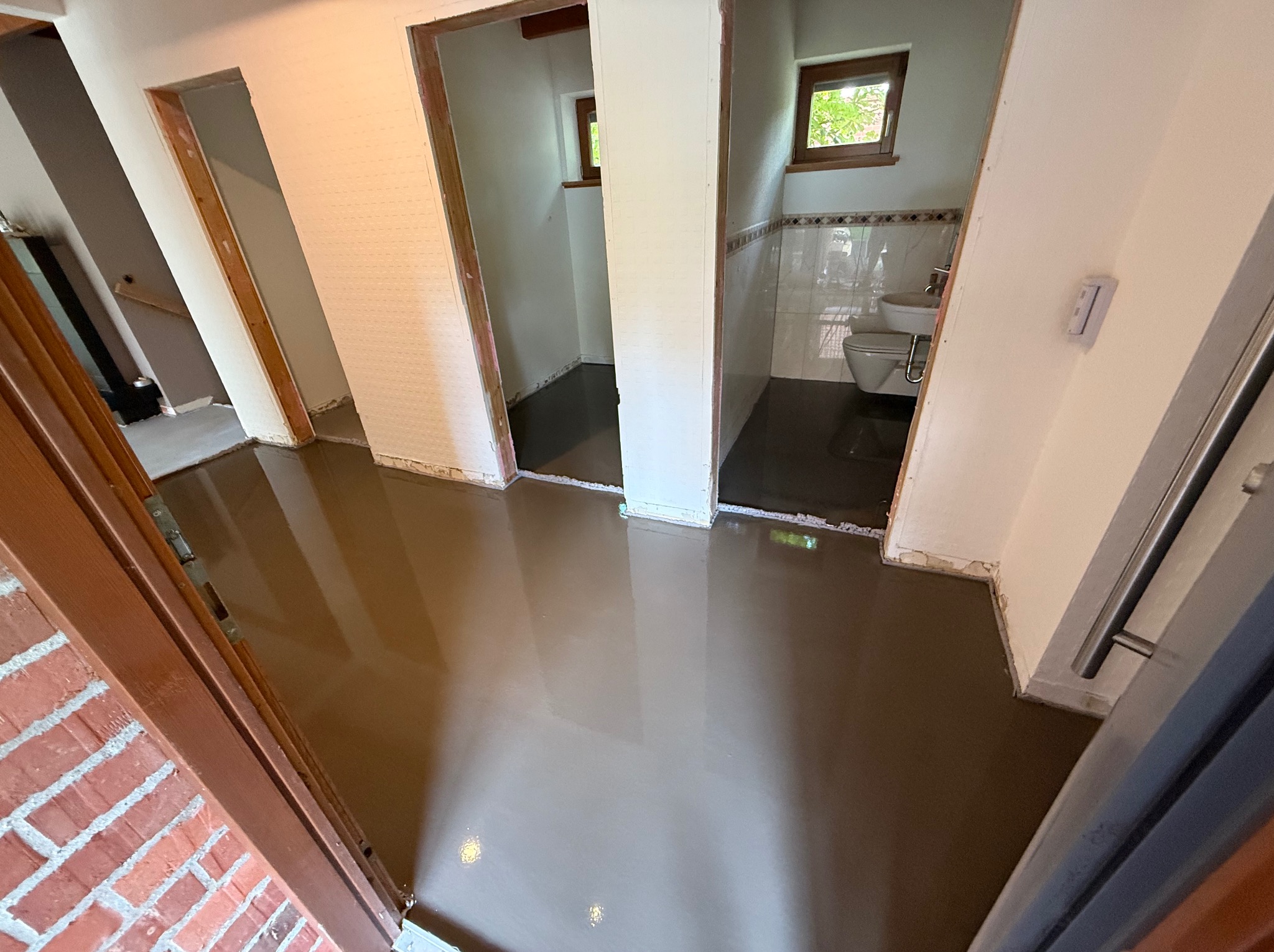 Wylany samopoziomujący podkład podłogowy w mieszkaniu w Stargardzie. Widok z perspektywy wejścia, z widocznymi otworami drzwiowymi do innych pomieszczeń.