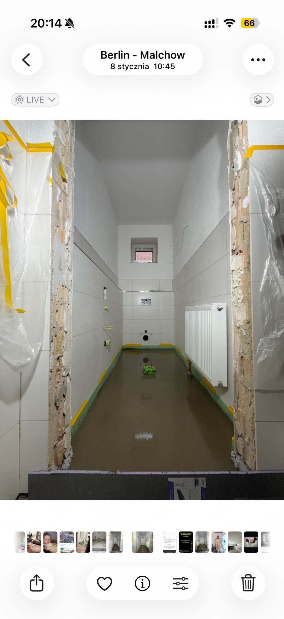 Wnętrze łazienki w trakcie wylewania posadzki. Widoczne białe płytki na ścianach, grzejnik, zabezpieczone folią i taśmą żółtą framugi drzwi. Na podłodze wylana masa samopoziomująca.