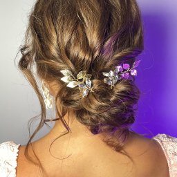 Małgorzata Liwuś - Upięcie włosów z ozdobnymi spinkami w kształcie listków, złote i srebrne, na brązowych, kręconych włosach, widok z tyłu, oświetlenie fioletowe.