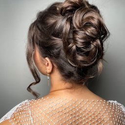 Małgorzata Liwuś - Elegancka fryzura upięta z brązowych włosów, widok z tyłu, z delikatnym upięciem i pojedynczym, zwisającym kolczykiem