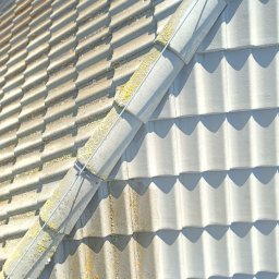 Czysta Strefa Mateusz Wójcik - Fragment dachu z dachówką, widoczny podział na czystą i zabrudzoną część, ukazujący efekt mycia. Zarys dachu z wyraźnym cieniem.