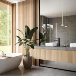 Nowoczesna łazienka z wolnostojącą wanną, podwójną umywalką nablatową i drewnianymi akcentami, doświetlona naturalnym światłem wpadającym przez duże okno z widokiem na zieleń.