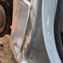 Maciej Grzęda MG Serwis - Fragment karoserii samochodu w trakcie naprawy blacharskiej, widoczne ślady szlifowania i spawania, przygotowanie do lakierowania.