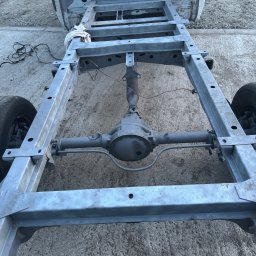 Maciej Grzęda MG Serwis - Oczyszczona i pomalowana rama samochodu z widocznym tylnym mostem, stojąca na betonowym podłożu, widoczne ślady szpachli na karoserii.