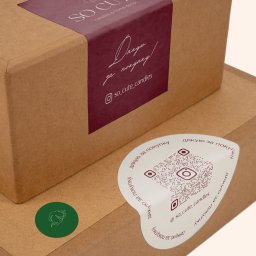 Maryna Slobodianiuk - Dwa kartonowe pudełka z naklejkami: prostokątną z logo 'SO CUTE' i okrągłą z kodem QR i podziękowaniem za zakup w języku ukraińskim.