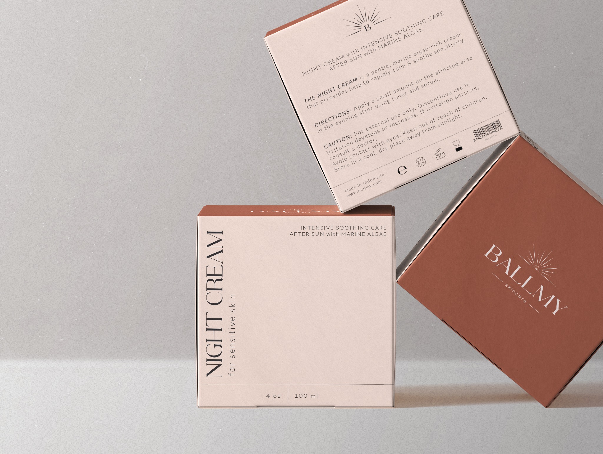 Dwa pudełka kremu na noc marki Ballmy, jedno w kolorze beżowym, drugie w odcieniu terakoty, leżące na jasnym tle.