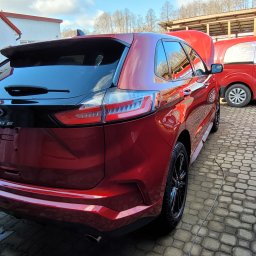 MSK KRZYSZTOF SZYMAŃSKI - Czerwony Ford Edge z otwartą maską, zaparkowany obok czerwonego samochodu serwisowego z napisem 'Mobilny Serwis Klimatyzacji' na kostce brukowej.