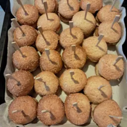 Mini burgery z sezamem na papierowej wyściółce, każdy z dekoracyjnym patyczkiem. Idealne na przyjęcia i eventy.