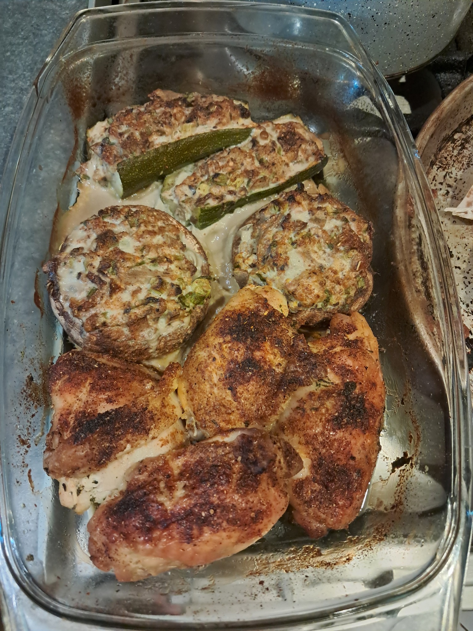 Pieczone dania w szklanym naczyniu: faszerowane cukinie, pieczarki i kurczak, gotowe do serwowania w Redzie. Domowe jedzenie z bliska.