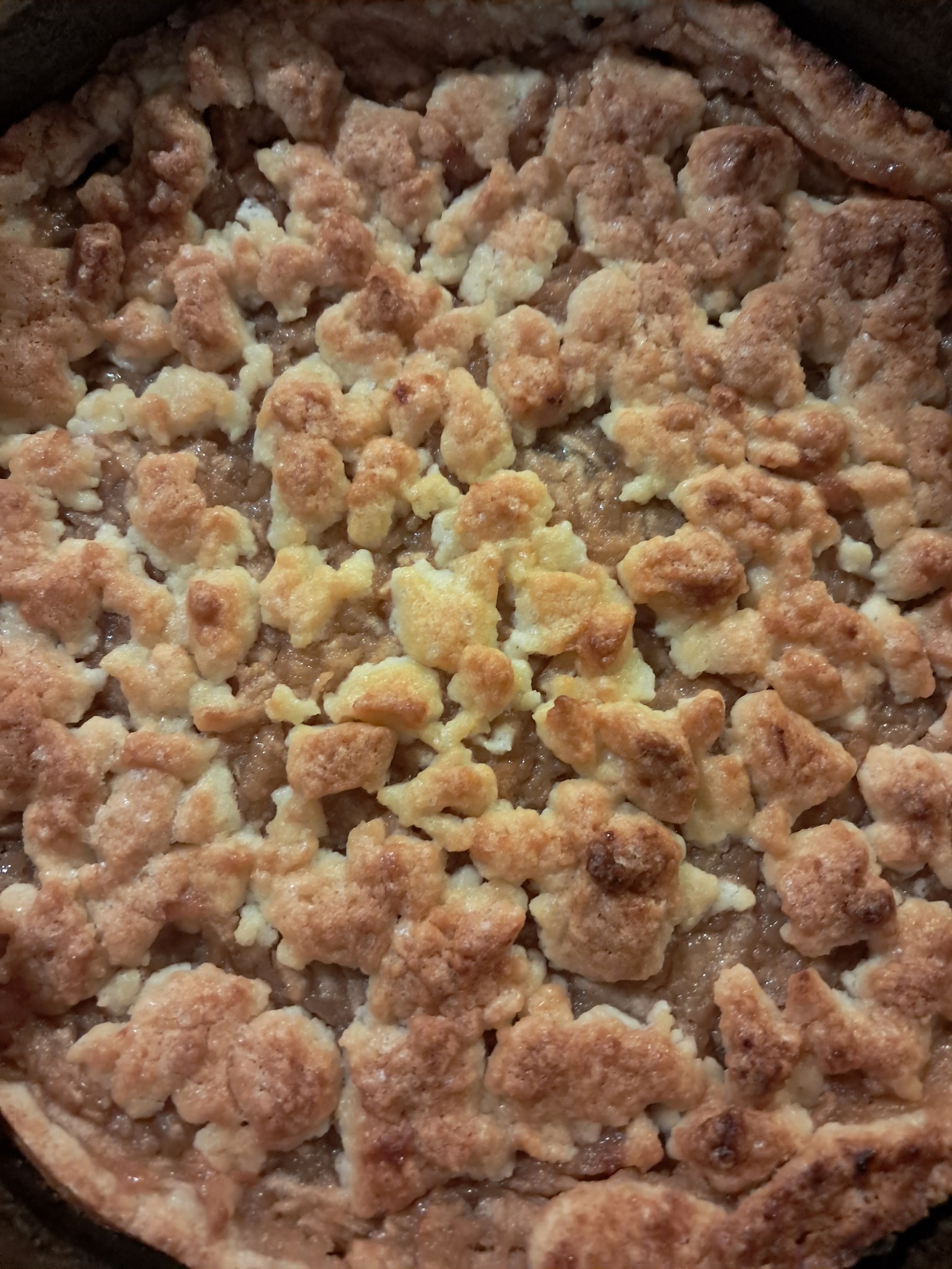 Kruchy placek z jabłkami z bliska, prezentujący złocistą kruszonkę i delikatne nadzienie. Idealny deser z cukierni na święta lub inną okazję.