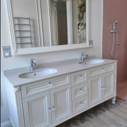 Styl mebel - Elegancka, kremowa szafka łazienkowa z dwoma umywalkami nablatowymi i kryształowymi gałkami, zwieńczona dużym lustrem z dekoracyjną ramą. Widoczny fragment ściany z różowymi płytkami i prysznicem.