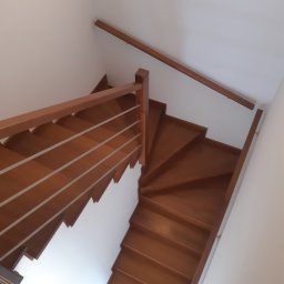 P.P.H.U.Heban - Wewnętrzne, spiralne schody z drewna z metalowymi prętami balustrady, widok z góry, jasne wnętrze.