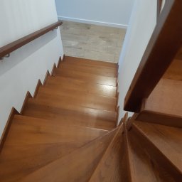 P.P.H.U.Heban - Wysoki kąt widzenia na kręte, jasne drewniane schody z poręczą, białe ściany i podłoga z paneli w tle.