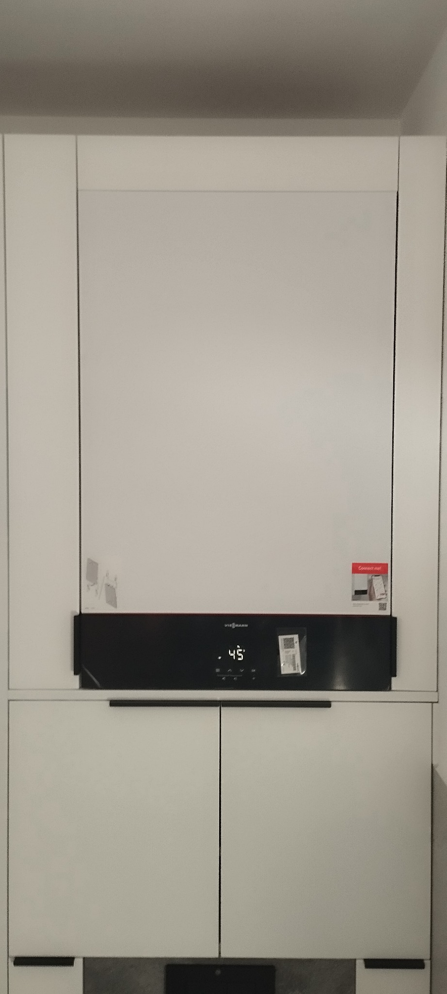 Nowoczesny piec gazowy Viessmann zabudowany w białej szafce kuchennej, widoczny czarny panel sterowania z wyświetlaną temperaturą 45 stopni Celsjusza oraz naklejki informacyjne na obudowie.