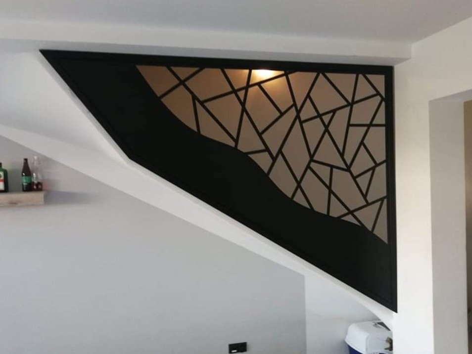 Nowoczesna, czarna barierka schodowa z geometrycznym wzorem i falistym elementem dekoracyjnym, zamontowana przy białych schodach w minimalistycznym wnętrzu.