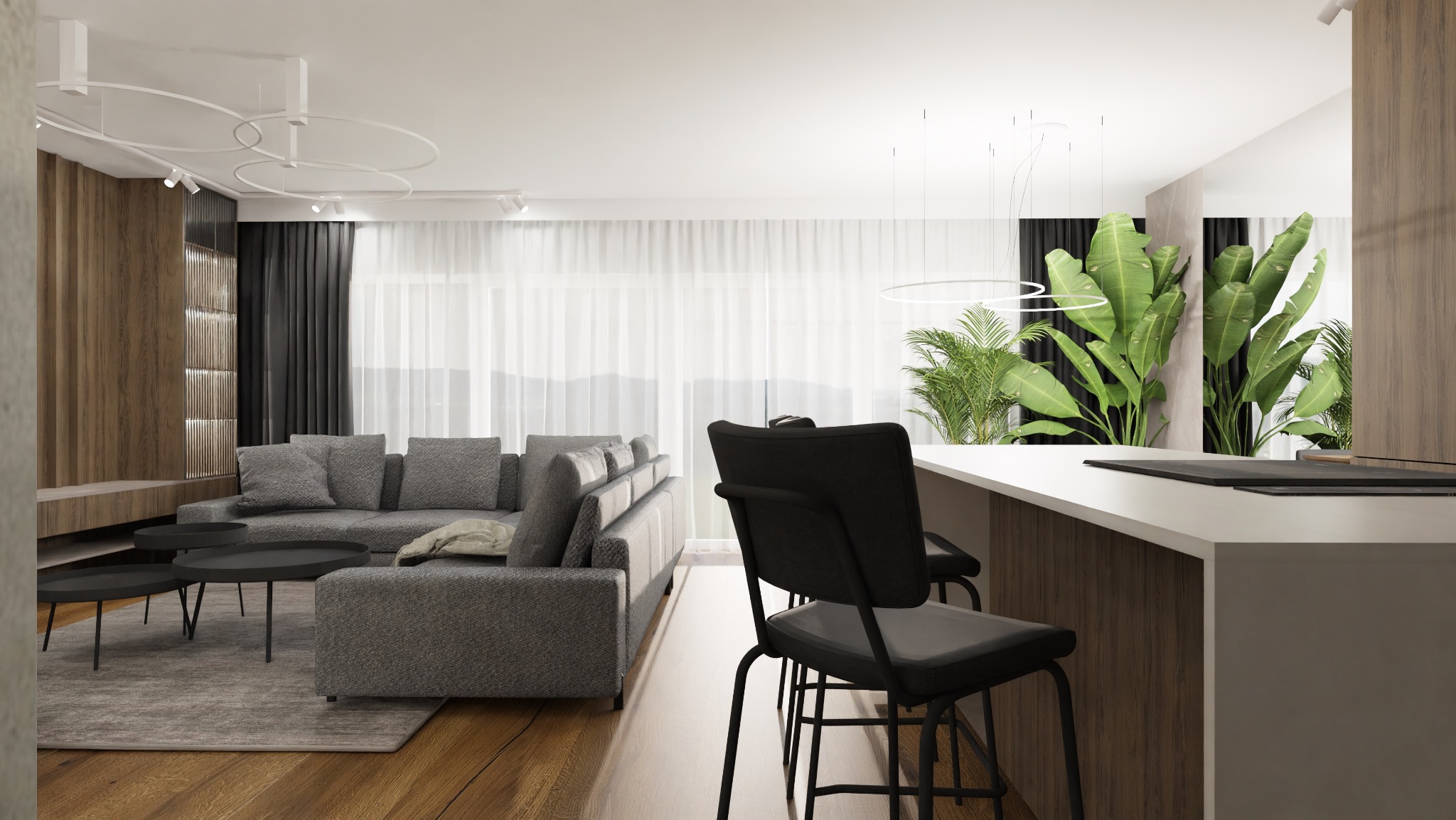 Nowoczesne wnętrze z szarą sofą, drewnianą zabudową, wyspą kuchenną z czarnymi hokerami i dużymi roślinami doniczkowymi.