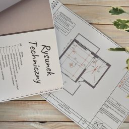 Miauart - Rysunek techniczny instalacji elektrycznej i oświetlenia mieszkania w Warszawie, z detalami opraw stropowych, lamp wiszących i listew sufitowych, leżący na drewnianym biurku.