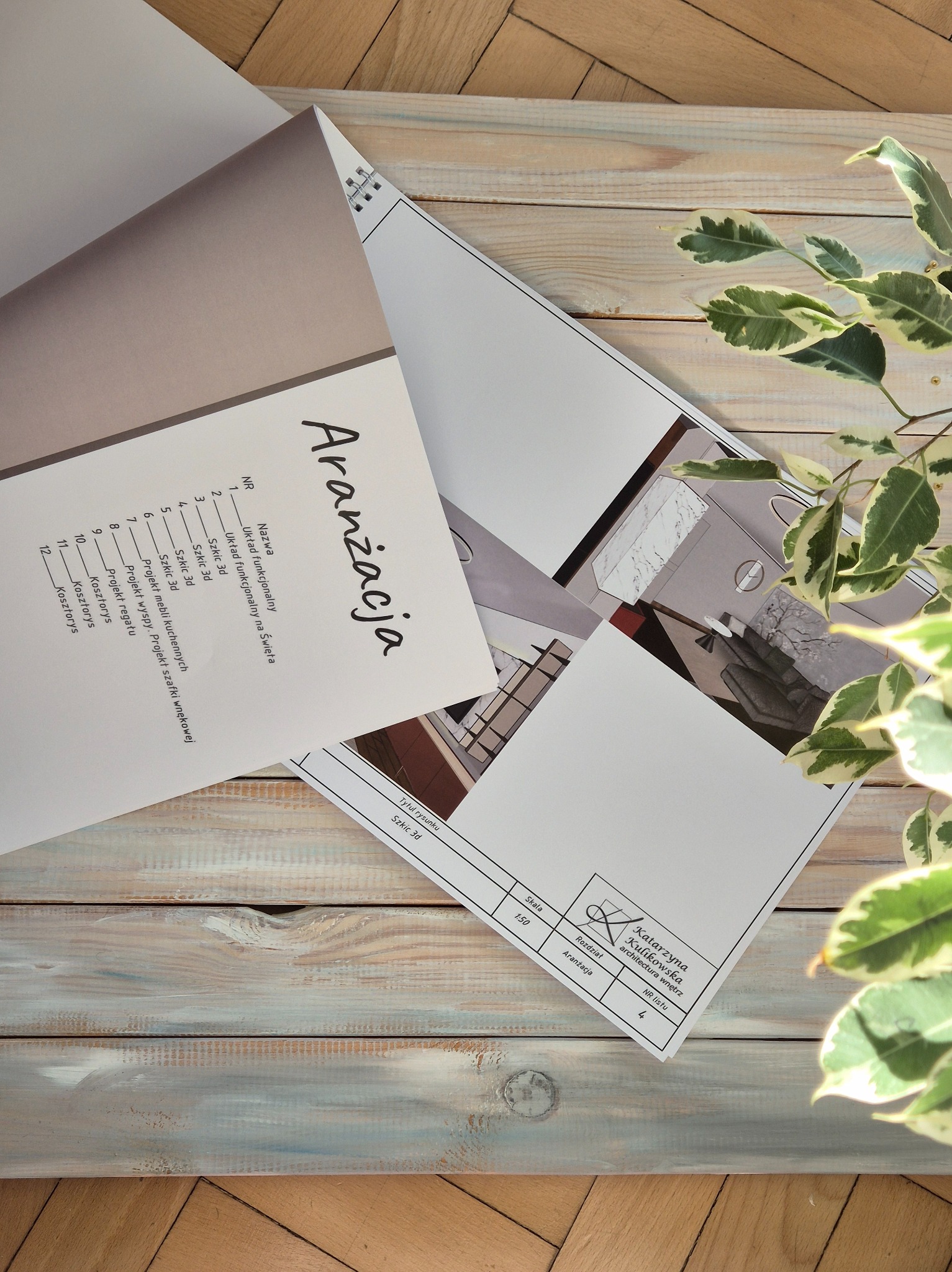 Szkice 3D wnętrz w otwartym segregatorze z napisem 'Aranżacja', leżące na drewnianym blacie, obok zielonej rośliny doniczkowej.