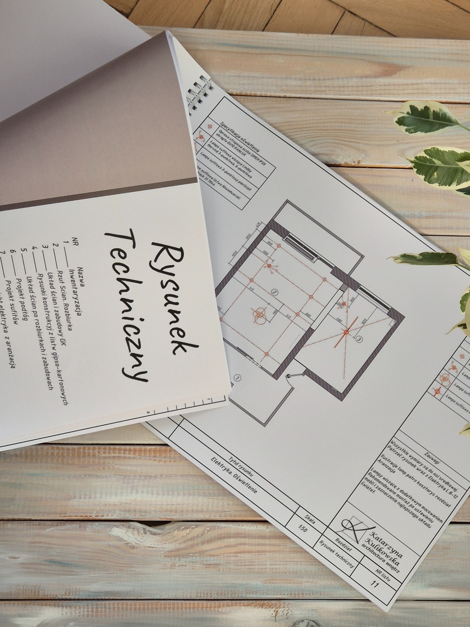 Rysunek techniczny instalacji elektrycznej i oświetlenia mieszkania w Warszawie, z detalami opraw stropowych, lamp wiszących i listew sufitowych, leżący na drewnianym biurku.