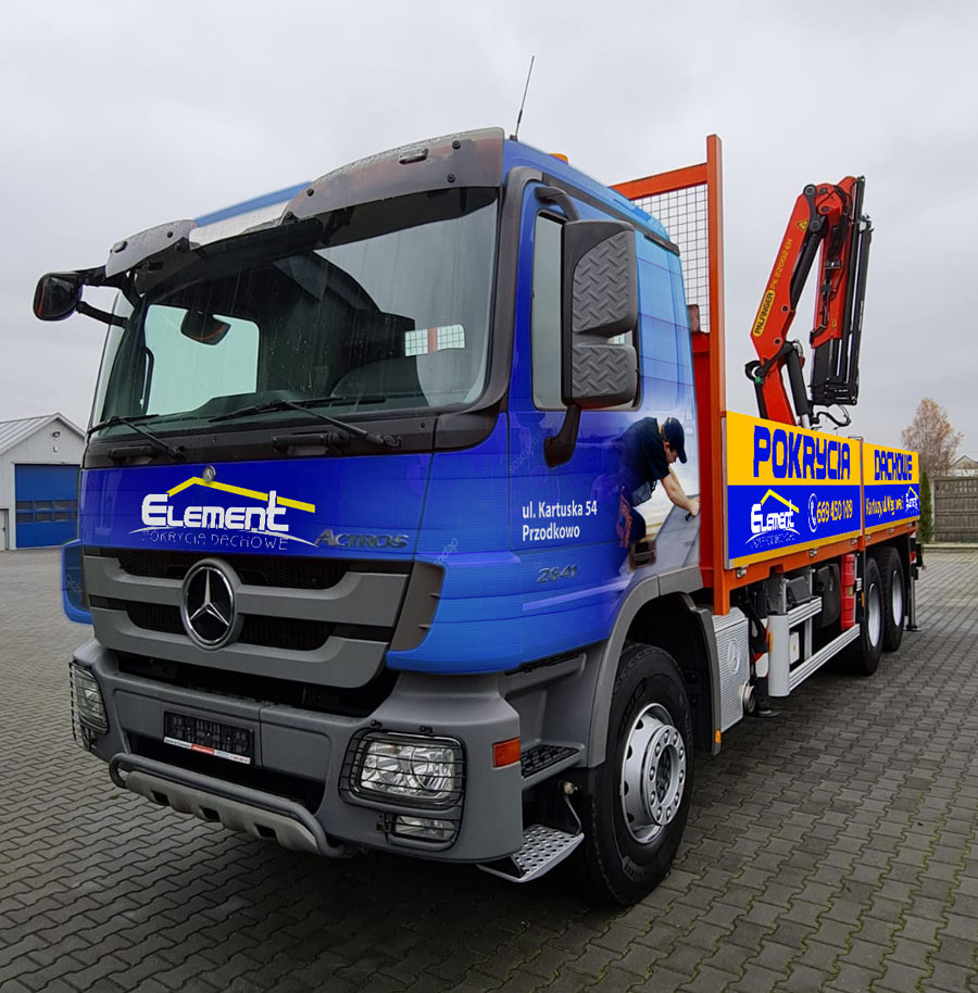 Ciężarówka firmy dekarskiej Element Pokrycia Dachowe z dźwigiem Palfinger, oklejona reklamami firmy, z pracownikiem wchodzącym do kabiny, zaparkowana na kostce brukowej.