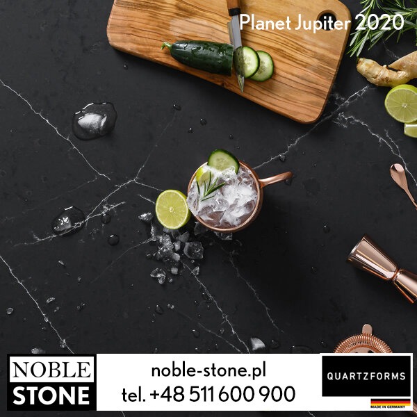 Czarny blat kamienny z białymi żyłami, z drinkiem w miedzianym kubku, limonką i ogórkiem. Drewniana deska z warzywami i narzędzia barmańskie.