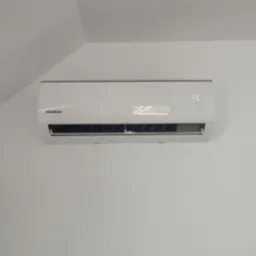 Biała klimatyzacja Kaisai z wyświetlaczem temperatury (17 stopni) zamontowana na białej ścianie pod skosem dachu.