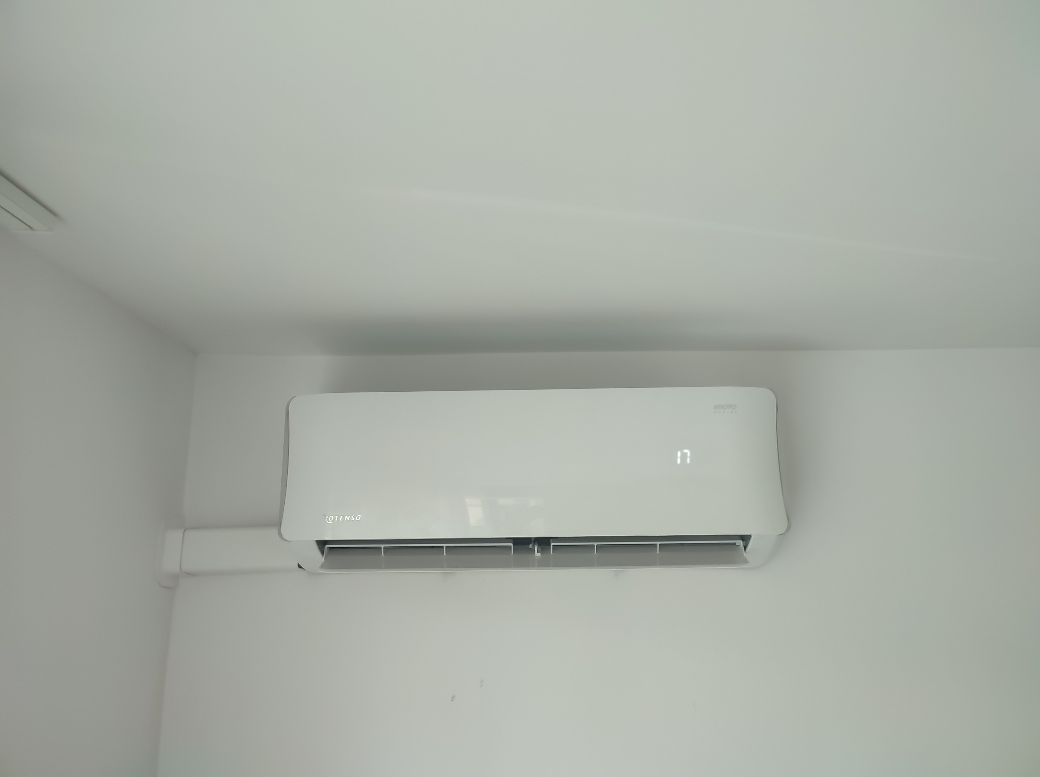 Biały klimatyzator marki Rotenso zamontowany na białej ścianie, wyświetlający temperaturę 17 stopni Celsjusza.