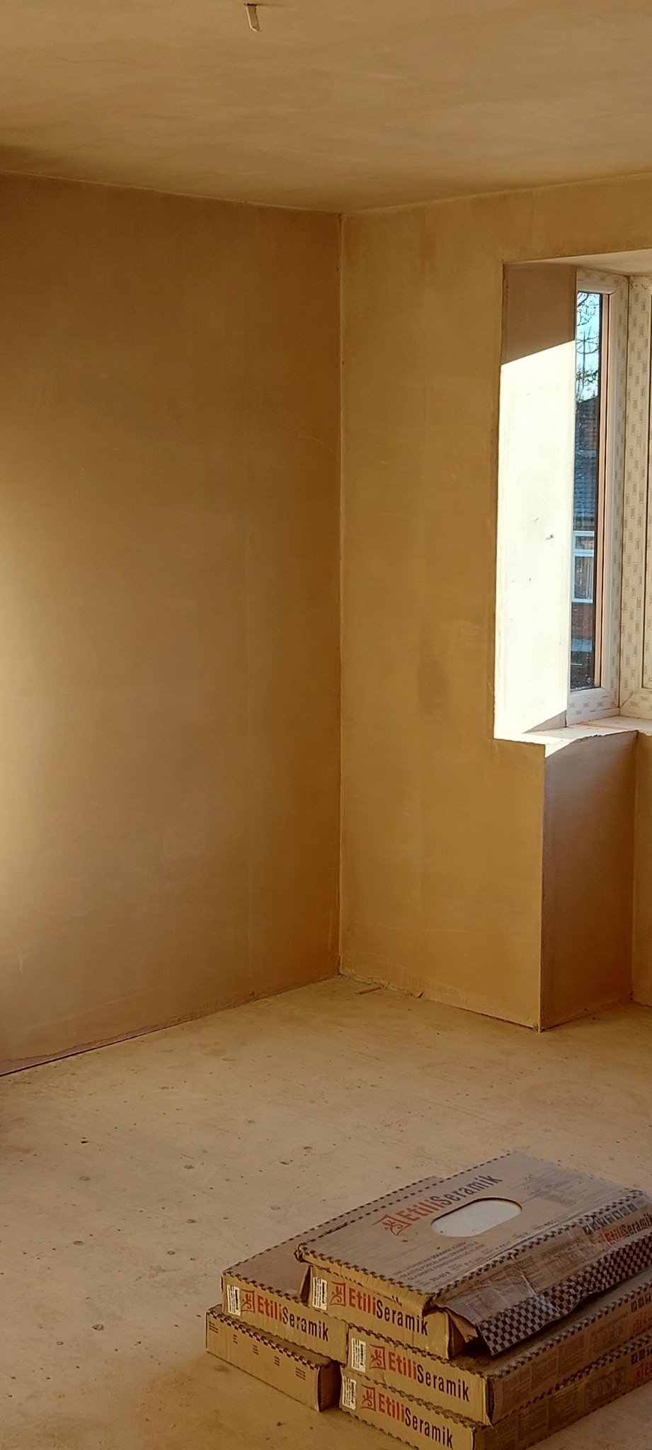 Pokój po szpachlowaniu z przygotowanymi kartonami płytek Etili Seramik w rogu, gotowy do dalszych prac wykończeniowych.