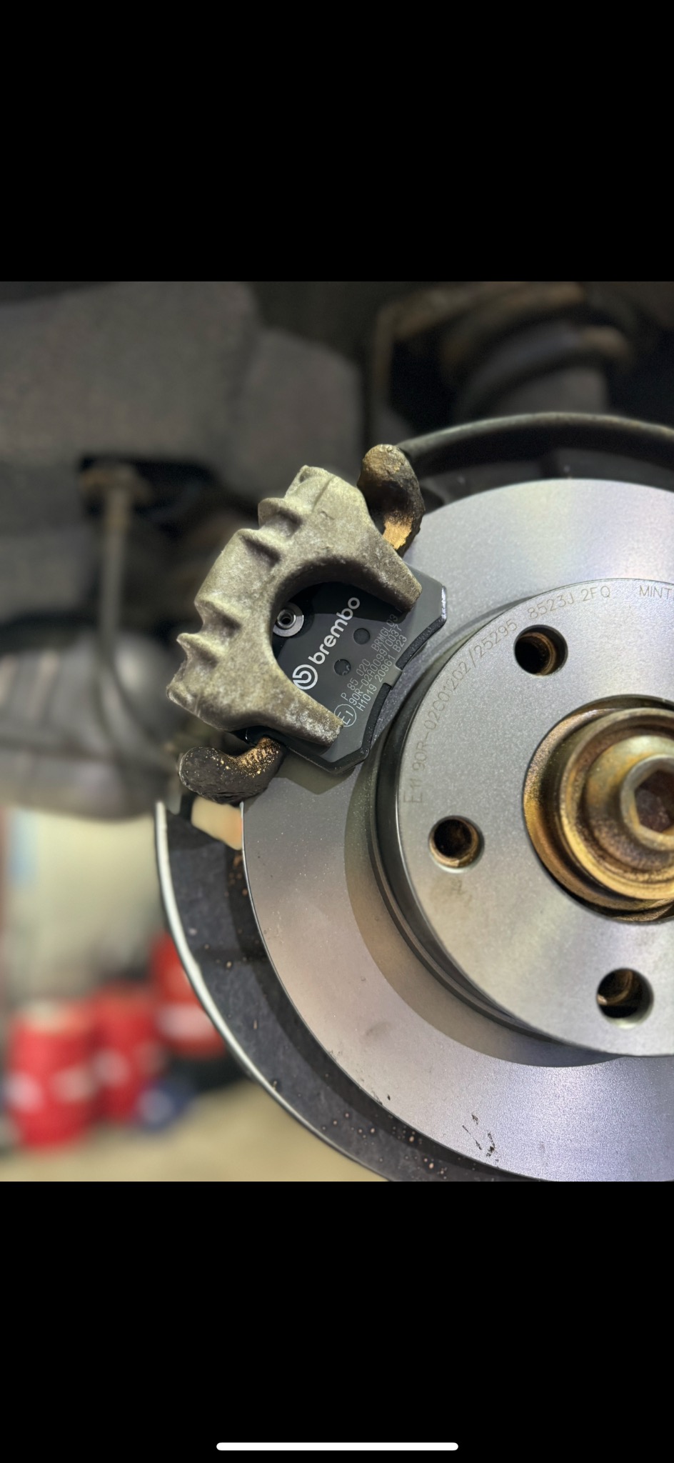 Nowe klocki hamulcowe marki Brembo zamontowane na tarczy hamulcowej. Widoczne oznaczenia na klockach i tarczy.