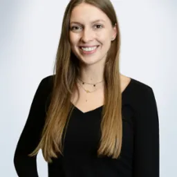 Portret uśmiechniętej kobiety w czarnej bluzce na jasnym tle, z delikatną biżuterią i bransoletką, wykonany w studio w Poznaniu.