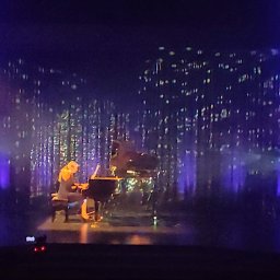 Art-Live Sp. z o.o. - Pianistka grająca na scenie z oświetleniem punktowym w kolorze fioletowym i dekoracyjnym tłem przypominającym deszcz gwiazd.