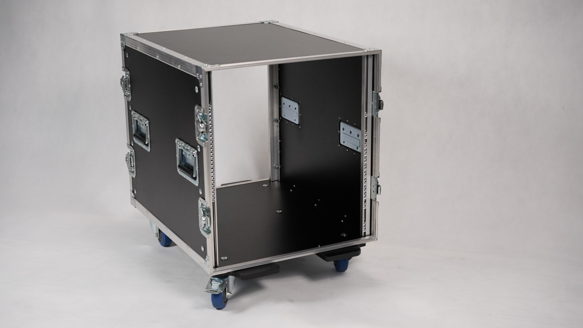 Pusta skrzynia transportowa na kółkach z uchwytami i metalowymi okuciami, przeznaczona do przewozu sprzętu oświetleniowego lub nagłośnieniowego.