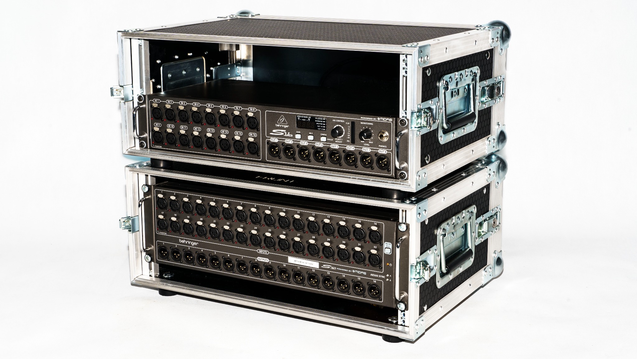 Dwa miksery Behringer S32 i S16 w skrzyniach transportowych rack, widoczne liczne wejścia i wyjścia XLR.