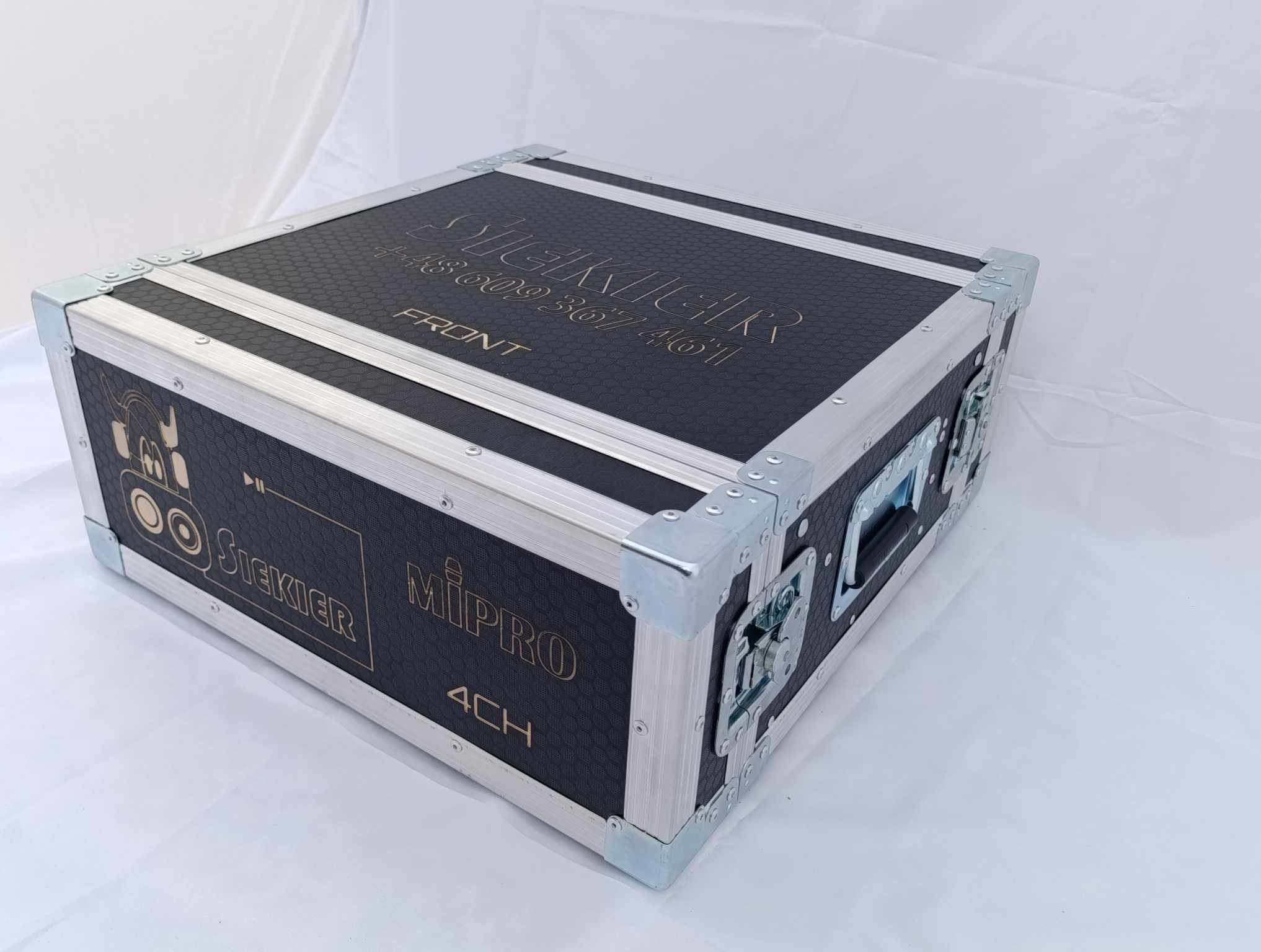 Czarna skrzynia transportowa na sprzęt audio z metalowymi narożnikami, widoczne logo firm Siekier i Mipro oraz numer telefonu.