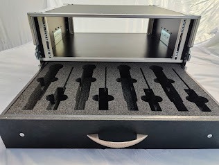 Otwarty case transportowy z piankowym wypełnieniem, przeznaczony do przechowywania mikrofonów. Widoczny uchwyt do wysuwania szuflady.