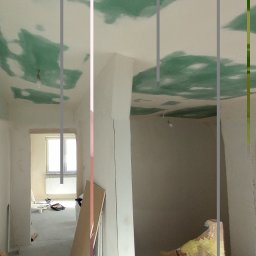 Usługi Ogólnobudowlane Michał Muzeja - Wnętrze w trakcie prac wykończeniowych: sufit z widocznymi plamami po nałożeniu warstwy wyrównującej, ściany w stanie surowym, widoczne płyty przy ścianie, w tle okno z grzejnikiem.