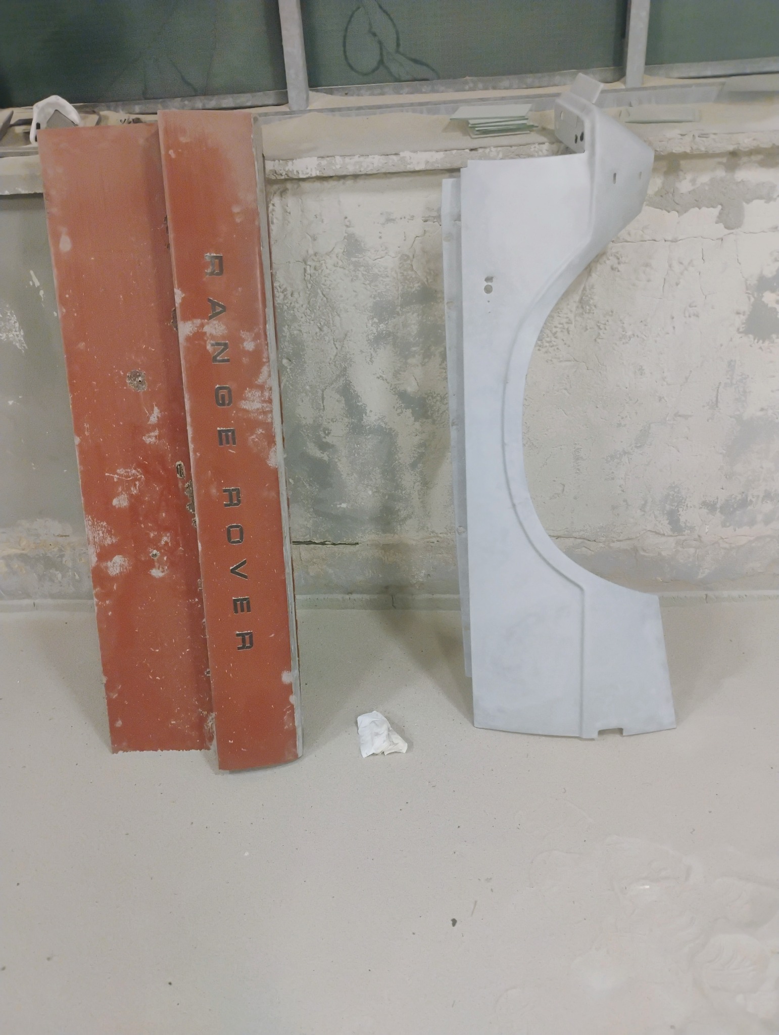 Elementy karoserii Range Rover: drzwi z napisem i błotnik w szarym podkładzie lakierniczym, przygotowane do dalszych prac lakierniczych.