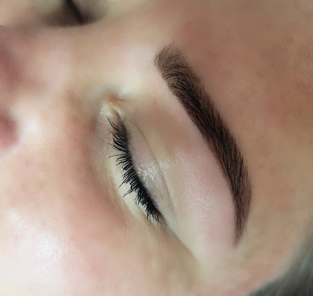 Zamknięte oko kobiety z wyraźnie zdefiniowanymi, ciemnymi brwiami po zabiegu stylizacji, widoczne rzęsy.