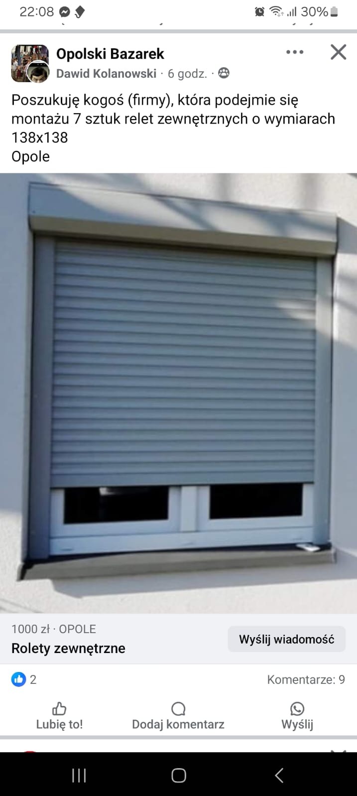 Zasłonięte okno szarą roletą zewnętrzną, widok z bliska na elewację budynku.