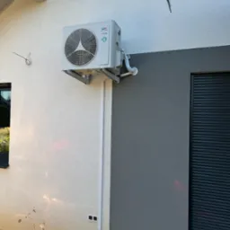 Zamontowana jednostka zewnętrzna klimatyzacji na elewacji budynku w Komorowie, z widocznymi przewodami i osłonami instalacyjnymi.