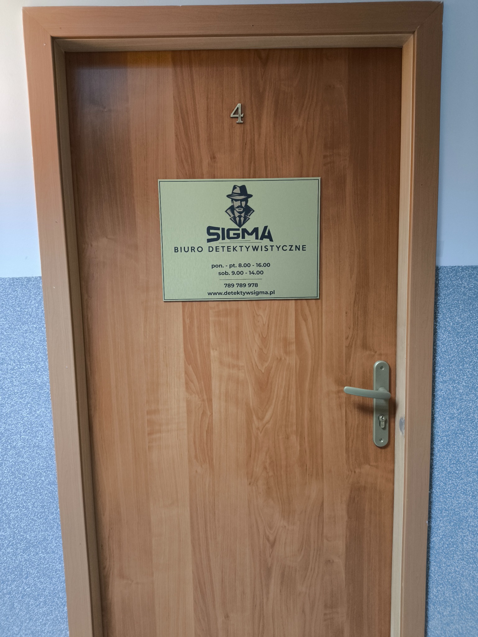Drzwi do biura detektywistycznego Sigma z numerem 4, tabliczka z godzinami otwarcia i danymi kontaktowymi.