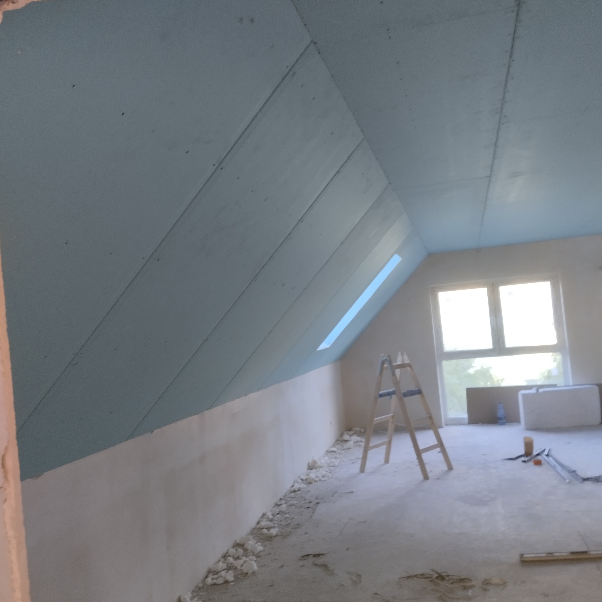 Montaż płyt karton gips na poddaszu w Warszawie, widoczna drabina i częściowo wykończona ściana.
