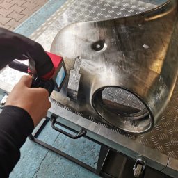 Czyszczenie Laserem - Kontrola grubości powłoki antykorozyjnej na elemencie karoserii pojazdu za pomocą miernika elektronicznego, widoczne ślady po piaskowaniu.