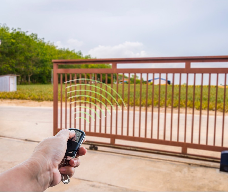 Otwieranie przesuwnej bramy wjazdowej za pomocą pilota; widoczne zielone fale radiowe.