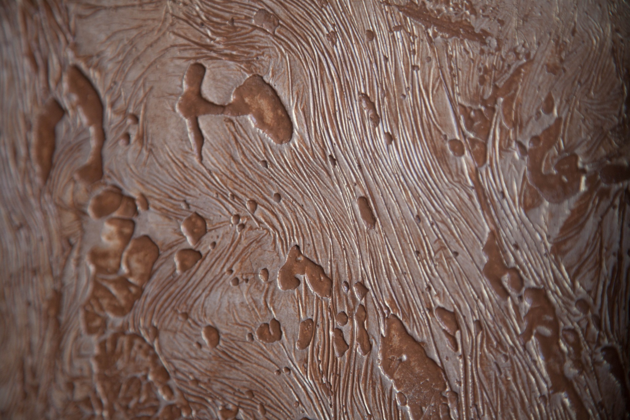 Tekstura ściany z efektem dekoracyjnym, imitującym drewno i metaliczne refleksy w odcieniach brązu i beżu, wykonana techniką reliefową.