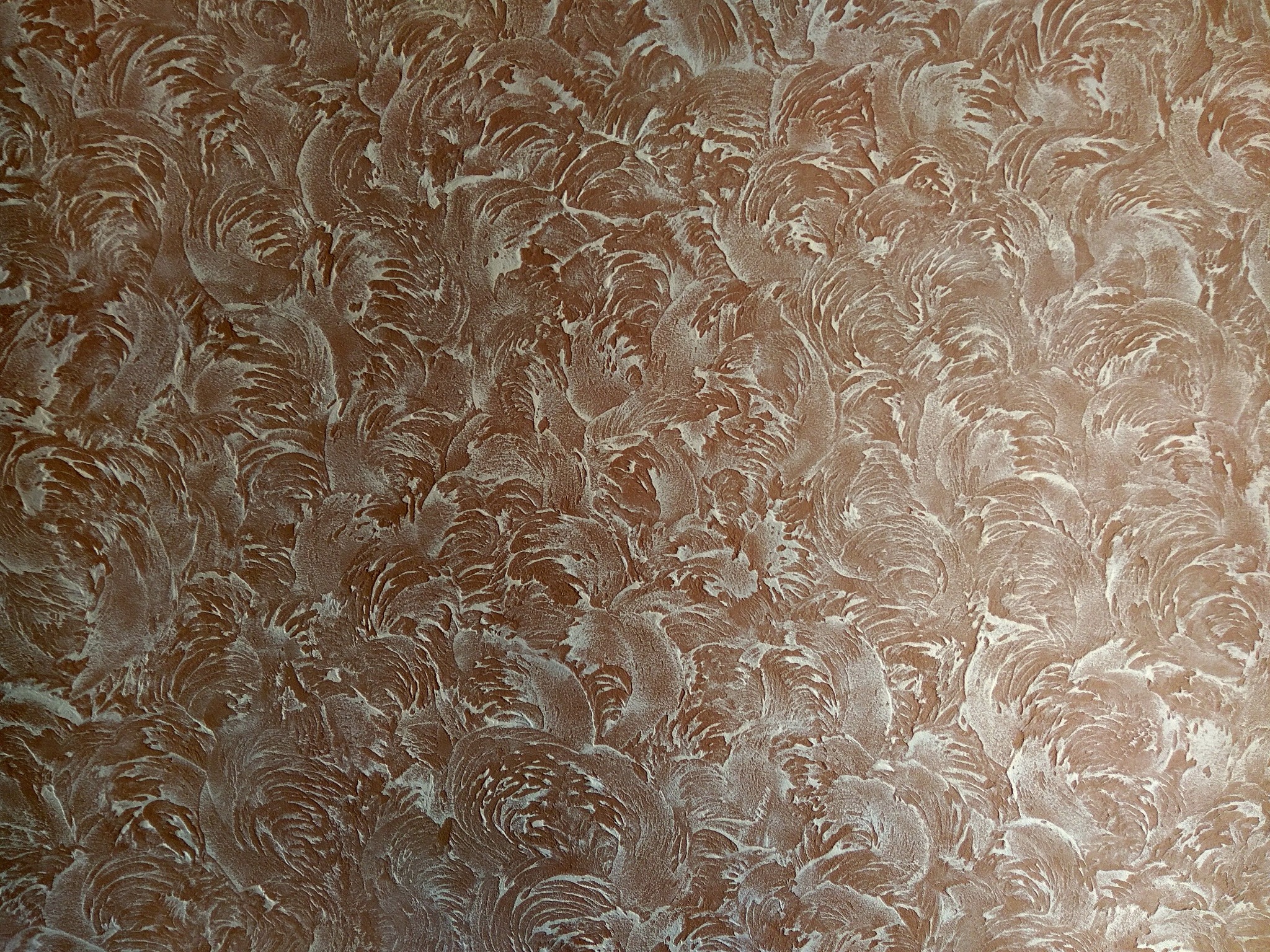 Brązowa ściana z dekoracyjną, białą, strukturalną farbą tworzącą wzór przypominający pióropusze.