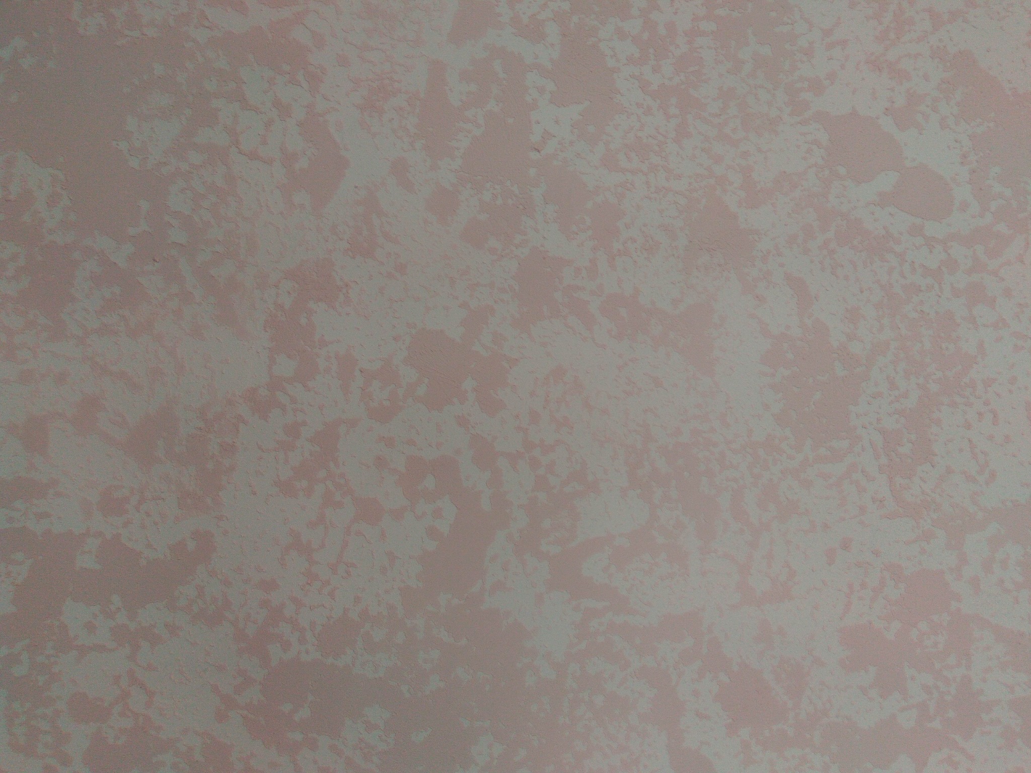 Różowa ściana z dekoracyjną, nieregularną strukturą, przypominającą efekt chmur lub marmuru.